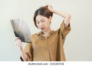 Suffering Summer Heat Stroke, Hot Weather, Tired Asian Young Woman, Girl Sweaty And Thirsty, Refreshing With Hand In Blowing, Wave Fan To Ventilation When Temperature High At Home, House.on Background