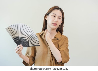 Suffering summer heat stroke, hot weather, tired asian young woman, girl sweaty and thirsty, refreshing with hand in blowing, wave fan to ventilation when temperature high at home, house.on background
