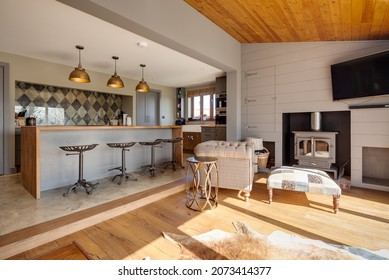 Suffolk, England - March 2018: Home Interior Kitchen Family Room Showing Breakfast Bar With Stools And Seating Area In Front Of Wood Burning Stove