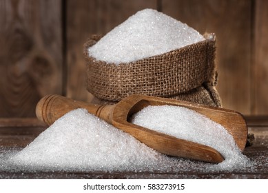 The sugar in a bag and spoon close-up on the old wooden background