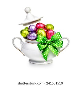 Sugar Bowl With Ribbon Bow Full Of Chocolate Candy Eggs Wrapped In Foil On White Background. Easter Themes