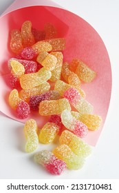 Sugar Coated Jelly Worms In A Pink Paper Bag On White Background