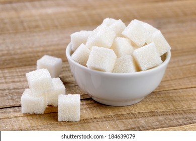 Sugar Cubes In Bowl On Wooden Table