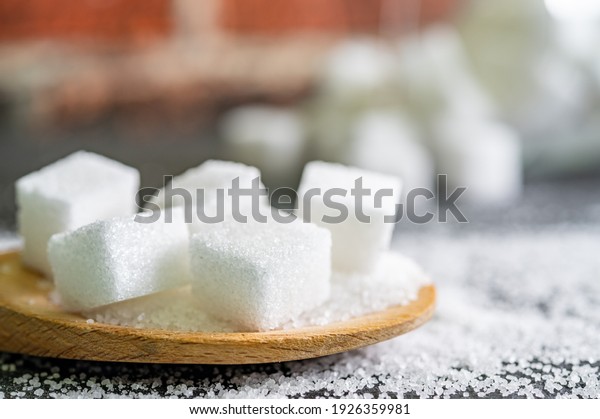 sugar cubes on black\
backround. Sugar is unhealthy nutrition and leads to obesity,\
diabetes, dental care