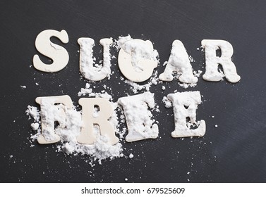 Sugar free written with wooden letters on black background.