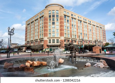 Sugar Land, Texas, United States of America - January 16, 2017.  View of Sugar Land Town Square, with fountain, sculptures, building, city traffic and people.