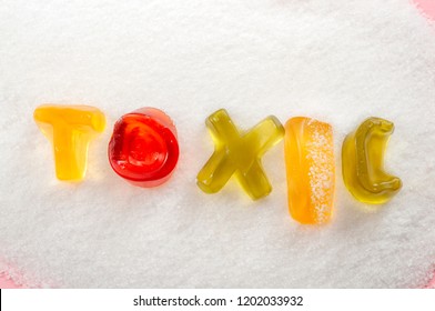 Sugar Is Poison, Unhealthy Diet And Refined Sugars Concept With Close Up On The Word Toxic Written Into A Pile Of White Granulated Sugar With Gummy Letters