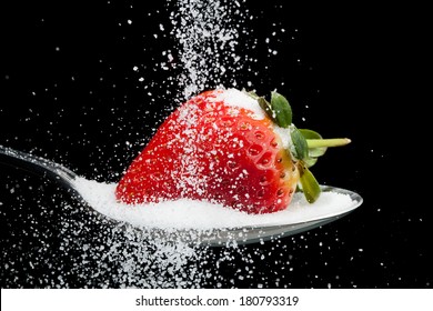 Sugar pouring over a strawberry on a spoon with a black background - Powered by Shutterstock