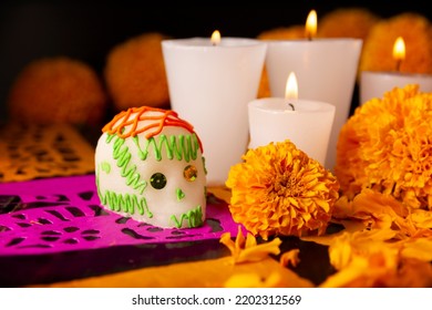 Sugar skulls with Candle, Cempasuchil flowers or Marigold and Papel Picado. Decoration traditionally used in altars for the celebration of the day of the dead in Mexico - Shutterstock ID 2202312569