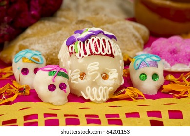 Sugar skulls from a day of the day Mexican holiday Dia de los Muertos with an offering background and cut out paper in front.