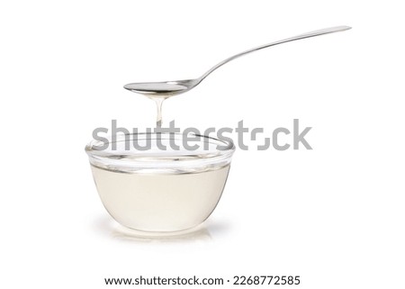Sugar syrup in glass bowl and spoon isolated on white background. 