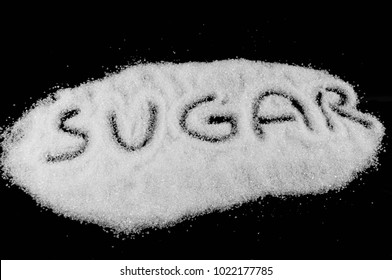 Sugar word written on white sugar isolated on black background.