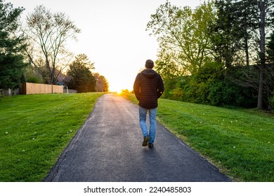 Sugarland Run Stream Valley Trail hike in Herndon, Fairfax county in Virginia spring with paved path road and silhouette of man walking towards sunset as hope concept - Powered by Shutterstock