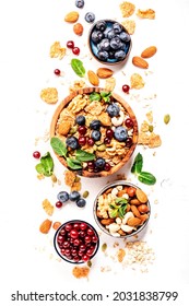 Sugarless muesli in bowl and ingredients for healthy breakfast. Granola, nuts, blueberry, cranberry, greek yoghurt, whole grain flakes on white table, top view
