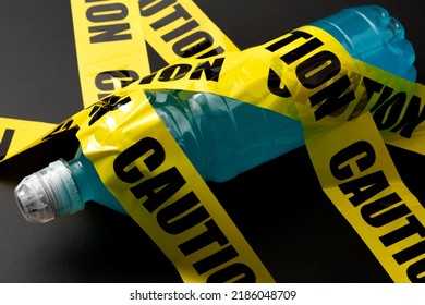Sugary Sports Drink Plastic Bottle Wrapped In Yellow Caution Tape Concept For Dangerous Liquid Candy, Dietary Warning About Beverages With High Sugar Content And Guidance Against Obesity