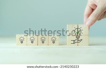 Suggestion and consulting concept. New idea, solution. Putting wooden cubes with light bulb on hand icon on beuatiful grey background and copy space. Business review, strategy suggestion for busines