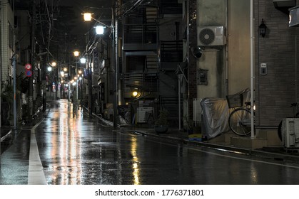 Suginami, Tokyo  Japan - July 4 2020: Night View Of An Empty Rain-soaked Street Illuminated By Streetlamps In A Suburban Part Of Western Tokyo