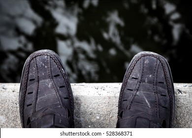 Zelfmoord en Major depressieve stoornis concept., Depressieve jongeman kijkt neer op zijn schoen en overweegt zelfmoord., Aan de rand van een brug met rivier hieronder.