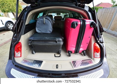 Suit cases packed for a holiday into an estate car.
