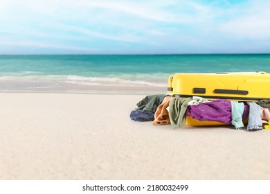 Suitcase with heap of clothes on sea beach. Travel concept - Shutterstock ID 2180032499
