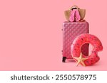 Suitcase with inflatable ring, starfish and beach accessories on pink background