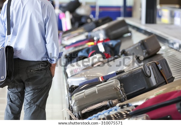 Suitcase on luggage conveyor belt in the baggage\
claim at airport