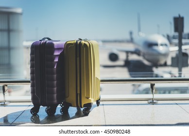 Suitcases in airport departure lounge, airplane in background, summer vacation concept, traveler suitcases in airport terminal waiting area, empty hall interior with large windows, focus on suitcases - Shutterstock ID 450980248