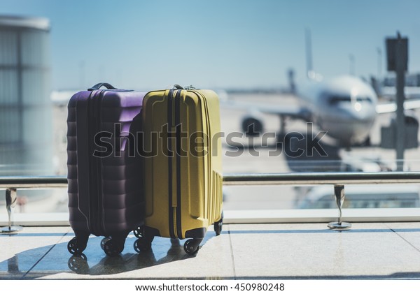 Suitcases in airport departure lounge, airplane\
in background, summer vacation concept, traveler suitcases in\
airport terminal waiting area, empty hall interior with large\
windows, focus on\
suitcases