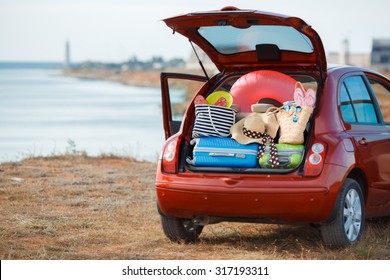 Suitcases and bags in trunk of car ready to depart for holidays. Moving boxes and suitcases in trunk of car, outdoors. trip, travel, sea. car on the beach with sea on background - Powered by Shutterstock