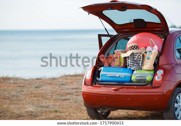 Suitcases and bags in\
trunk of car ready to depart for holidays. Moving boxes and\
suitcases in trunk of car, outdoors. trip, travel, sea. car on the\
beach with sea on\
background