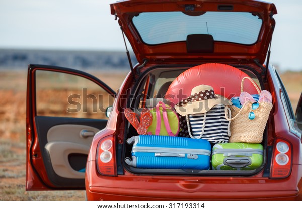 Suitcases and bags in\
trunk of car ready to depart for holidays. Moving boxes and\
suitcases in trunk of car, outdoors. trip, travel, sea. car on the\
beach with sea on\
background