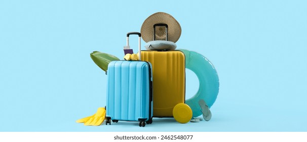Suitcases with beach accessories on blue background with space for text