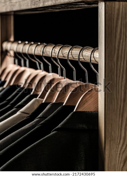 Suits for\
men hanging on the rack. Mens suits in different colors hanging on\
hanger in a retail clothes store,\
close-up.