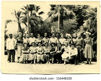 SUKHUMI - CIRCA 1964: group rest against of the park with palm trees, Sukhumi, Abkhazia, Georgia, USSR, 1964