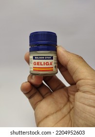 Sukoharjo. 22 September 2022. A Man's Hand Holds A Bottle Of Geliga Muscle Balm With A Dark Blue Tube Cap On A White Background.