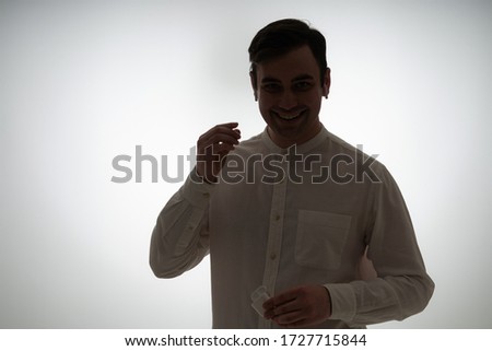 sulhuette of a guy with wireless earphones in white shirt