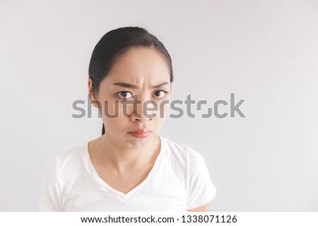 Sulk and grumpy face expression of Asian woman in white t-shirt. Concept of offended peevish and sulky.
