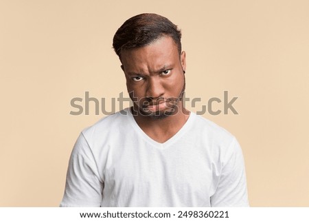 Sulky Face. Grumpy Afro Guy Looking At Camera Posing Over Yellow Background. Studio Shot