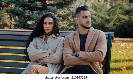 Sullen couple sitting on bench in park man and woman sit with arms crossed lovers quarrel ignoring each other angry arabic guy and curly offended girl feel sad sadness from conflict misunderstanding