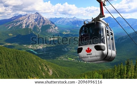 Sulphur Mountain Gondola on a blue sky with snow peaked Rocky Mountains background (Banff. Alberta. Canada)
