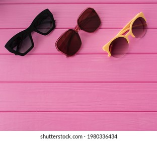 Summer Abstract Background Mockup Template Free Copy Space  For Text Pattern Sample Top View Above On Pink Wooden Board. Blank Empty Area For Inscription. Couple Stylish Black Sunglasses Fashionable