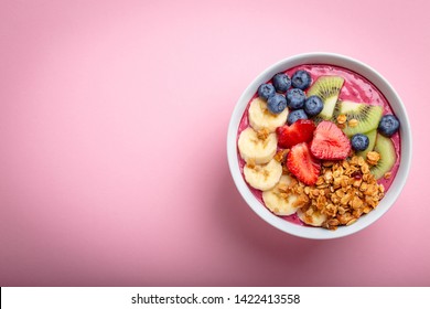 Summer acai smoothie bowl with strawberries, banana, blueberries, kiwi fruit and granola on pastel pink background. Breakfast bowl with fruit and cereal, close-up, top view, space for text - Powered by Shutterstock