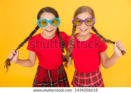 Summer accessory. Girls cute sisters similar outfits wear colorful sunglasses for summer season. Kids fashionable friends posing in sunglasses on yellow background. Summer fashion trend. Summer fun.