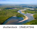 Summer aerial view of a plain river, a floodplain forest and a small village. The nature of central Chukotka. Travel across Russia. Anadyr River, Markovo village, Chukotka, Siberia, Russian Far East.