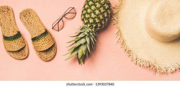 Summer apparel items. Flat-lay of summer flip flops, sunglasses, straw sunhat? and fresh pineapple over pastel pink background, top view, wide composition. Summer beach vacation concept - Powered by Shutterstock