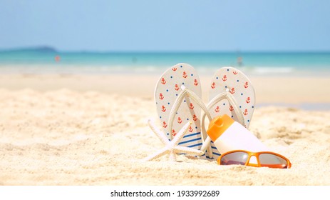 Summer Assessorieses. Planing To Travel With Sunblock And Sandal On The Beautiful Beach And Blue Sky Background. Tropical Fashion. Summer Fashion On Holiday Concept. 