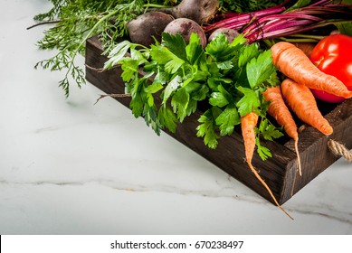 Summer, autumn harvest. Fresh organic farm vegetables in a wooden box on a white marble table - beets, carrots, parsley, tomatoes. Copy space