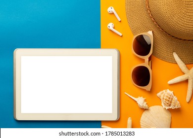 Summer Background With Blank Screen Tablet Computer And Beach Accessories - Sunglasses, Straw Hat On Vibrant Orange And Blue Table Top View With Copy Space.