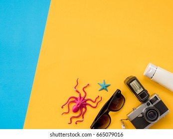 Summer Background, Summer holiday concept, Travel Concept with Untidy props are Sunscreen, Glasses, Camera, sea animal and hat on blue and yellow background. - Shutterstock ID 665079016