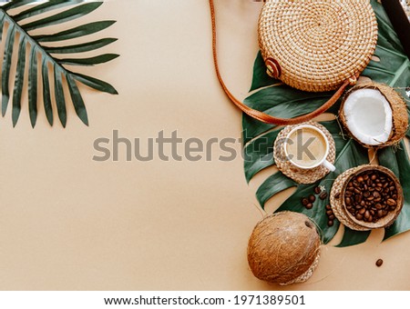 Summer background with Ratan bag, leaves monstera, coffee cup and coconut on brown background. Flat lay, top view